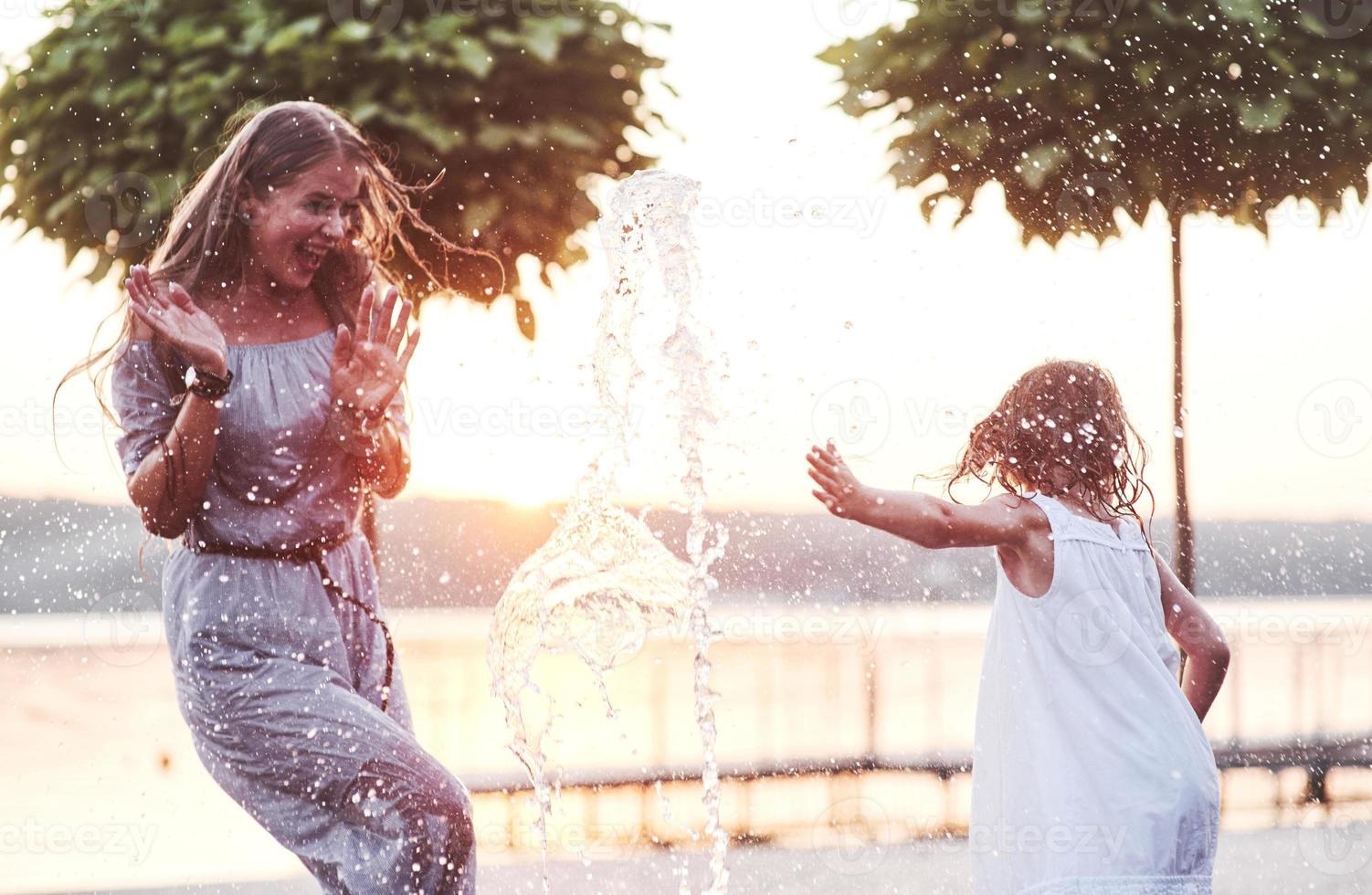 bonheur, figé dans le temps. par une chaude journée ensoleillée, la mère et sa fille décident d'utiliser une fontaine pour se rafraîchir et s'amuser avec photo