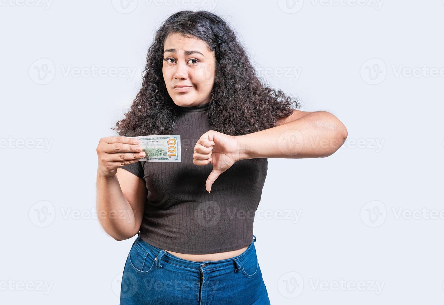 mécontent Jeune femme en portant une dollar facture avec pouce vers le bas isolé. triste fille en portant une une 100 dollar facture avec pouce vers le bas photo