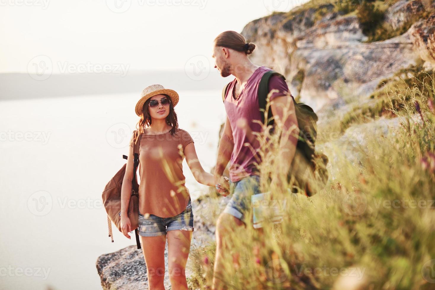 des gens magnifiques sur fond majestueux. un jeune couple a décidé de passer ses vacances de manière active au bord du magnifique rocher avec un lac en arrière-plan photo