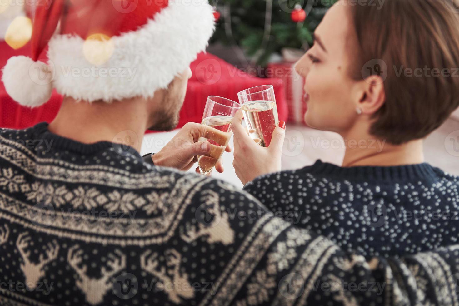 célébrer le nouvel an. frapper des verres. beau couple en vêtements de vacances s'assoit et s'embrasse. photo de dos