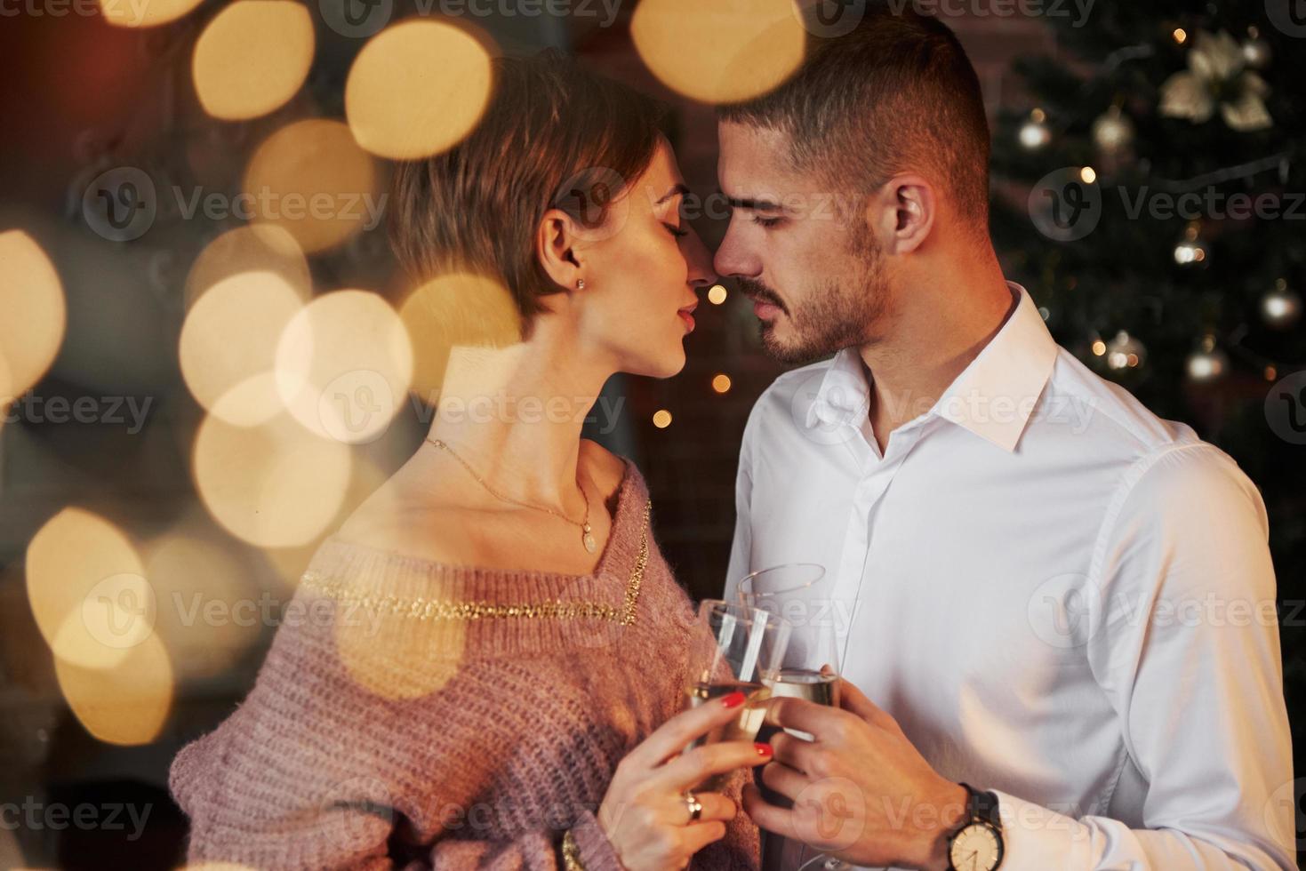 presque le baiser. joli couple célébrant le nouvel an à l'intérieur avec de beaux vêtements classiques sur eux photo