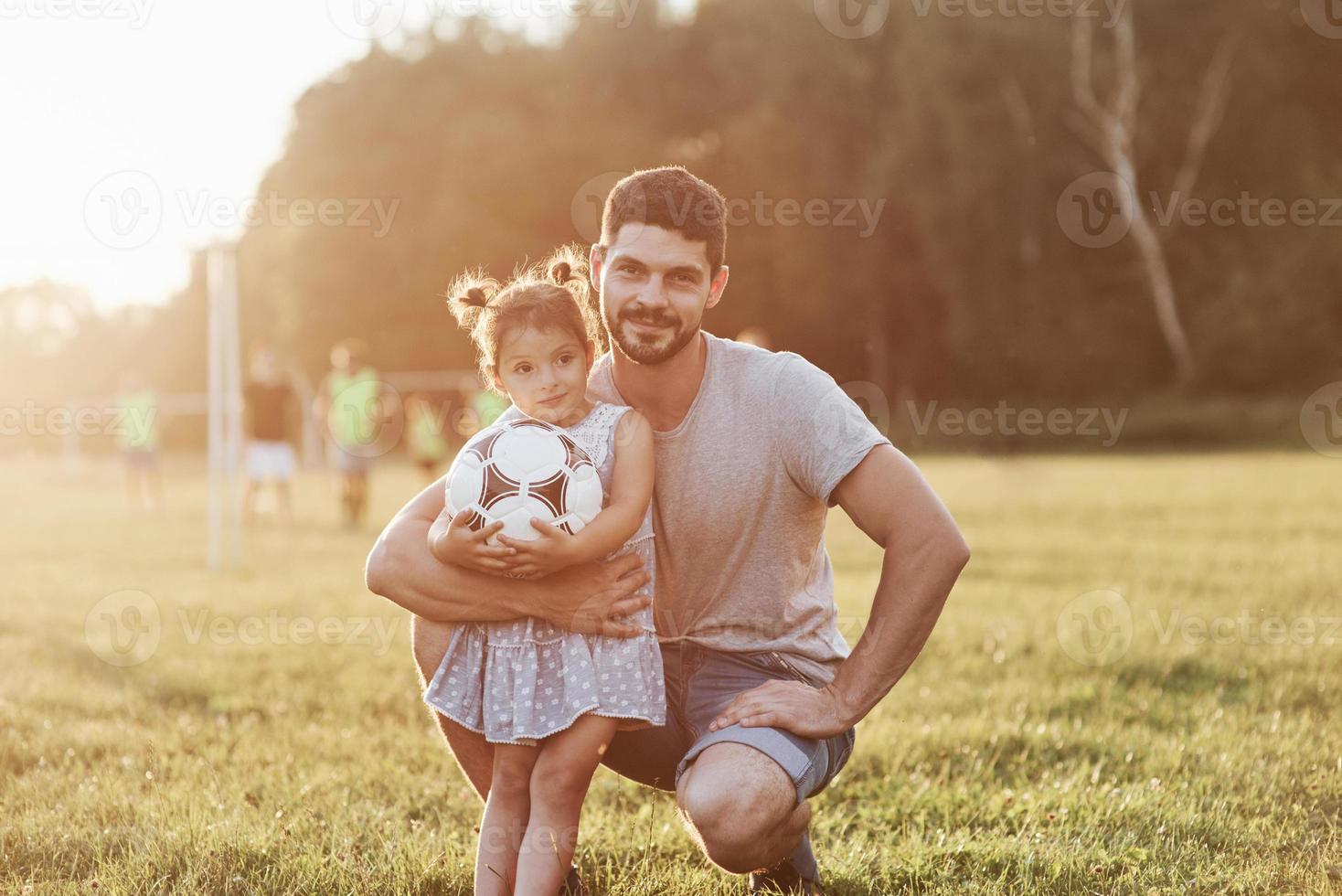 joli portrait. regardez la caméra s'il vous plaît. photo de papa avec sa fille dans une belle herbe et des bois en arrière-plan