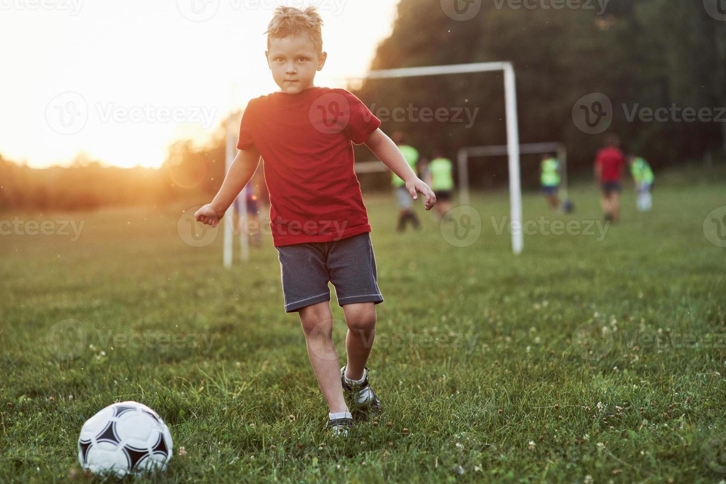 se sentir excité. garçon joue au football à une chaude journée ensoleillée et va marquer un but photo