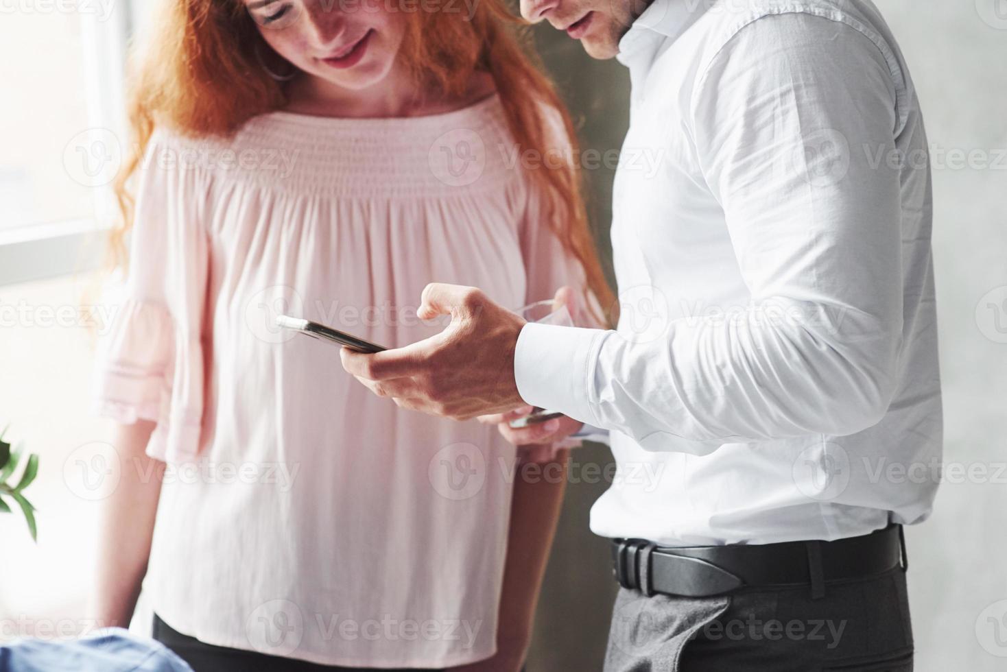 Man in office wear montrant des informations sur son téléphone à une fille de tête de lecture photo