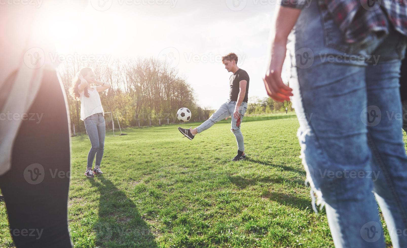 un groupe d'amis en tenue décontractée joue au football en plein air. les gens s'amusent et s'amusent. repos actif et coucher de soleil pittoresque photo