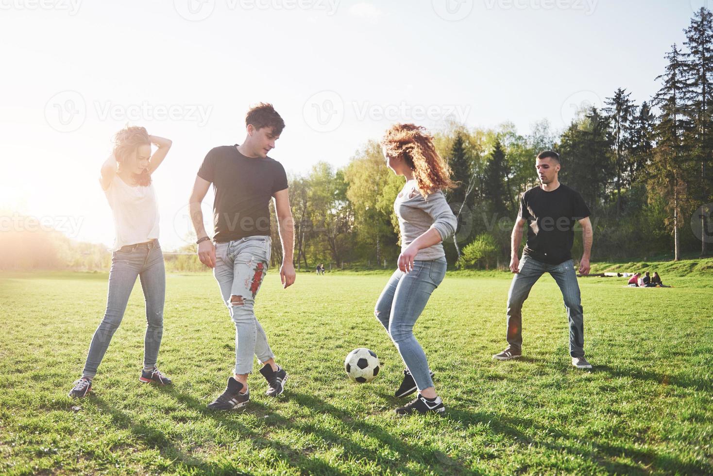 un groupe d'amis en tenue décontractée joue au football en plein air. les gens s'amusent et s'amusent. repos actif et coucher de soleil pittoresque photo