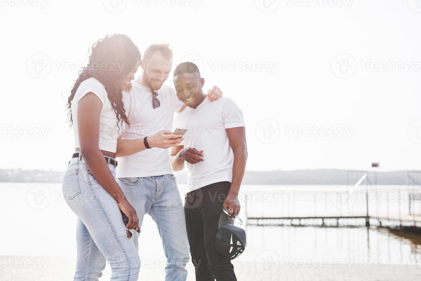 groupe d'amis heureux multiraciaux utilisant un gadget à l'extérieur. concept de bonheur et d'amitié multiethnique tous ensemble contre le racisme photo