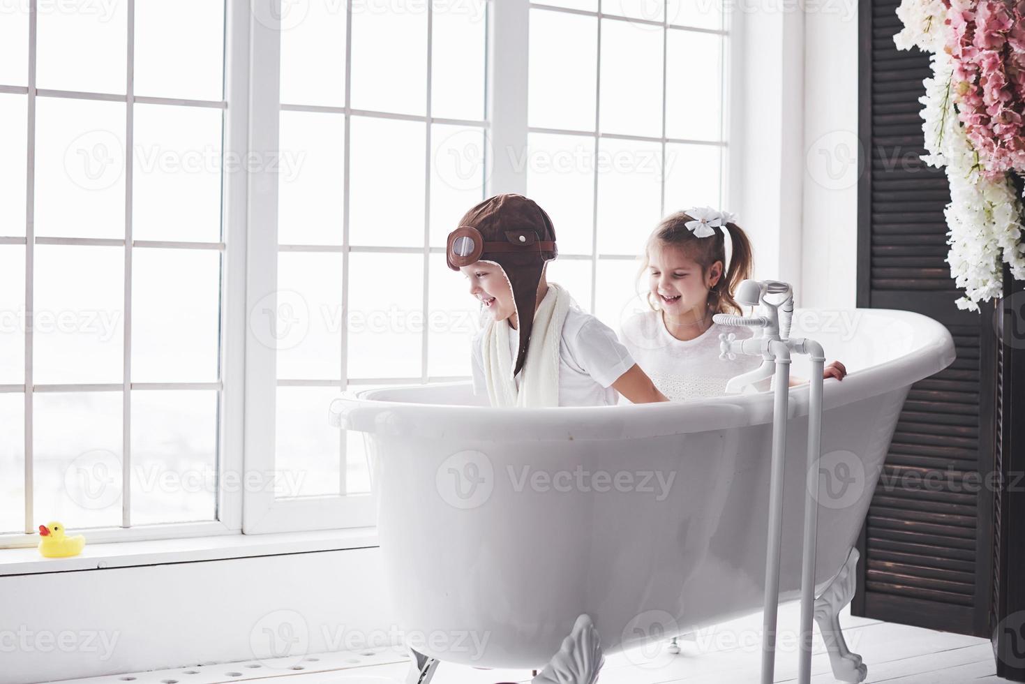 portrait d'une fille et d'un garçon au chapeau de pilote jouant dans la salle de bain chez les pilotes ou les marins. le concept de voyage, d'enfance et de réalisation de rêves photo