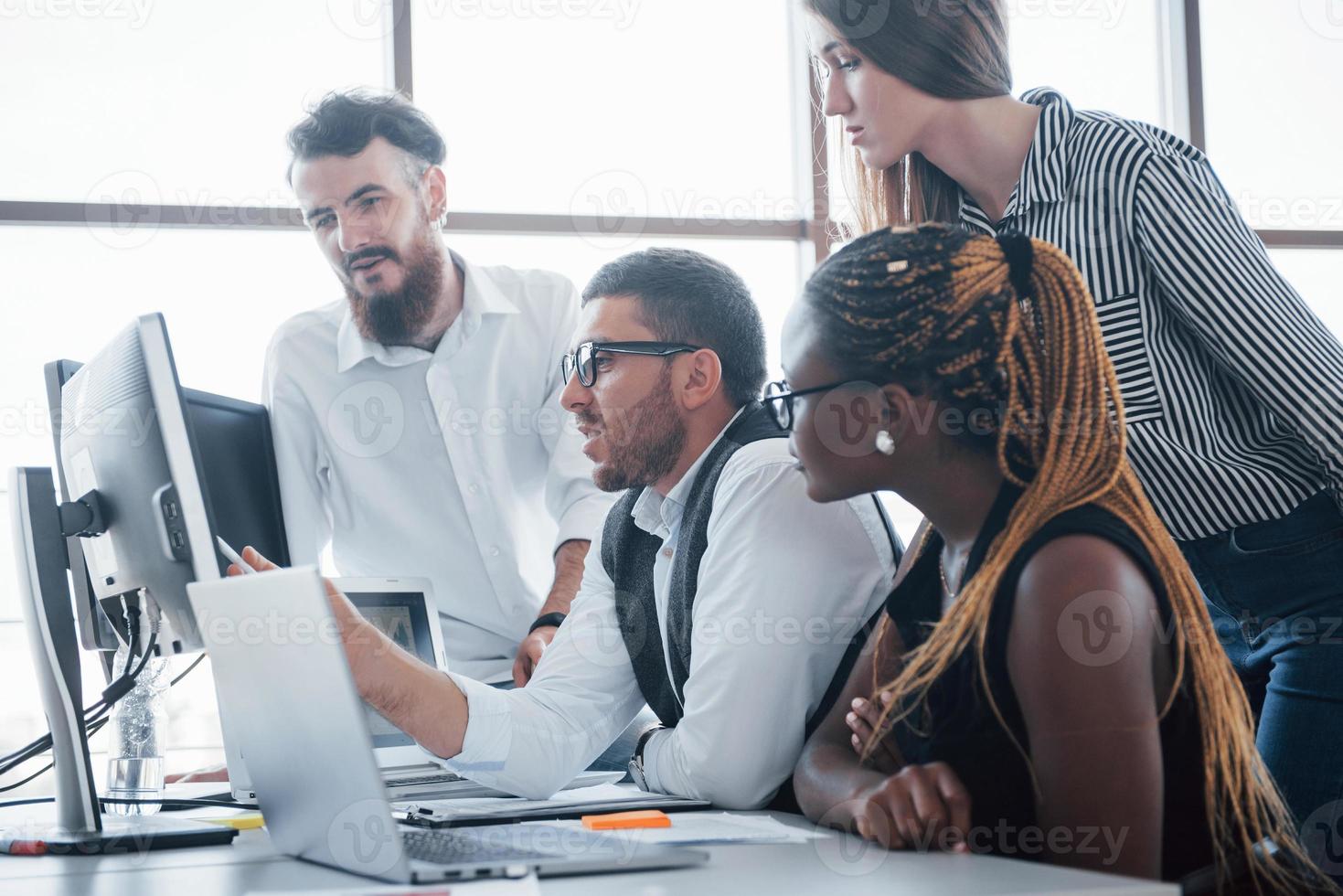 jeunes employés assis au bureau à la table et utilisant un ordinateur portable, un concept de réunion de remue-méninges de travail d'équipe. photo