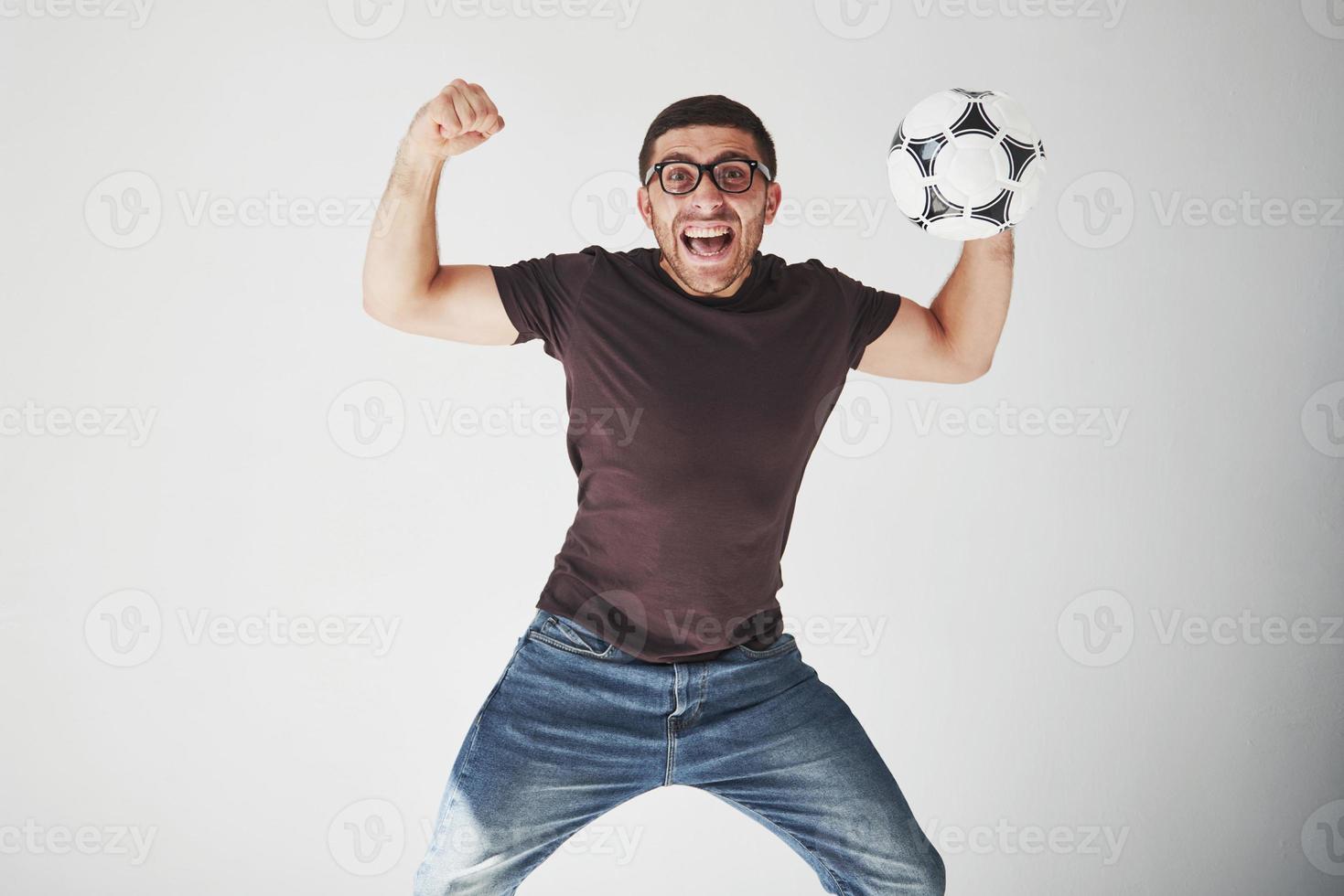 fan de football excité avec un ballon de football isolé sur fond blanc. il saute est heureux et effectue divers tours d'encouragement pour son équipe préférée photo