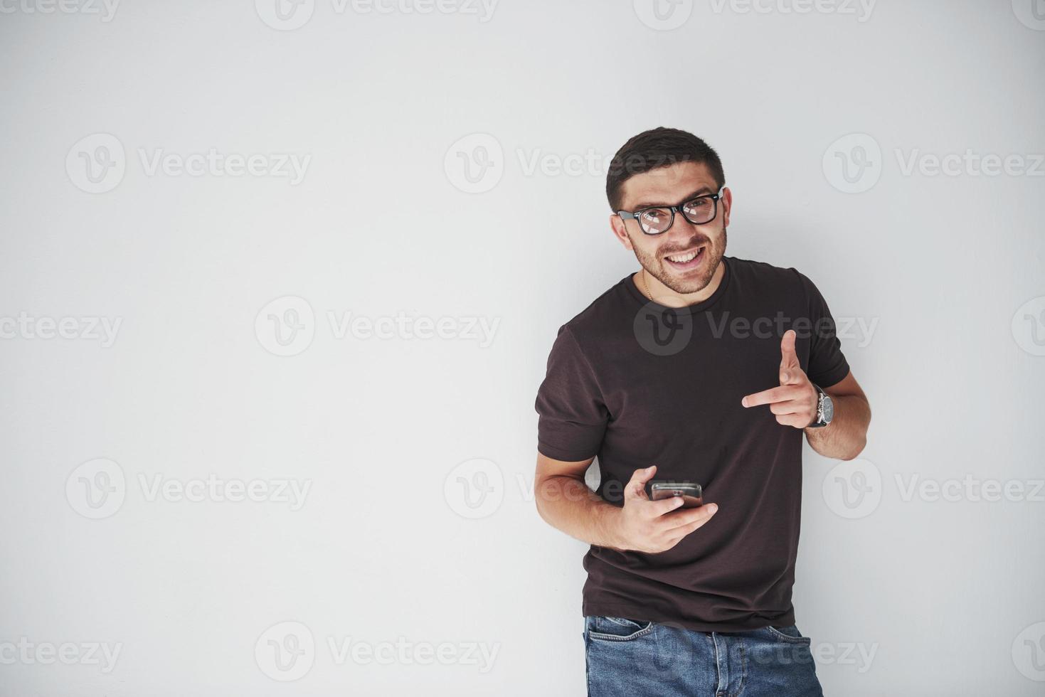 jeune homme heureux décontracté habillé avec un téléphone intelligent sur fond blanc photo