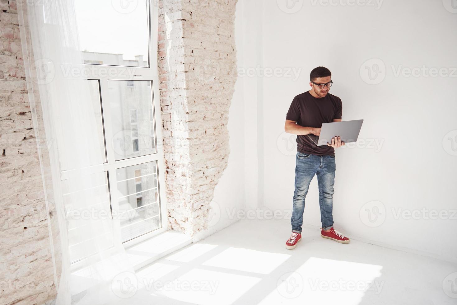 beau jeune homme avec ordinateur portable et vérifier son emploi du temps sur fond blanc photo