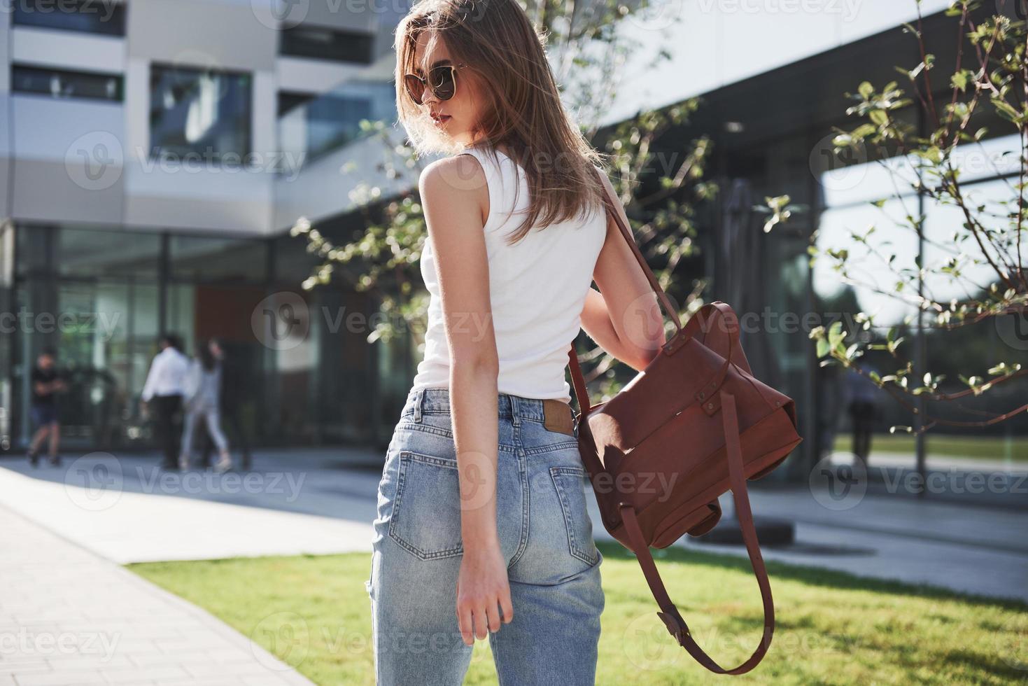 belle et heureuse jeune étudiante avec sac à dos près du campus de l'université. concept d'éducation et de loisirs photo