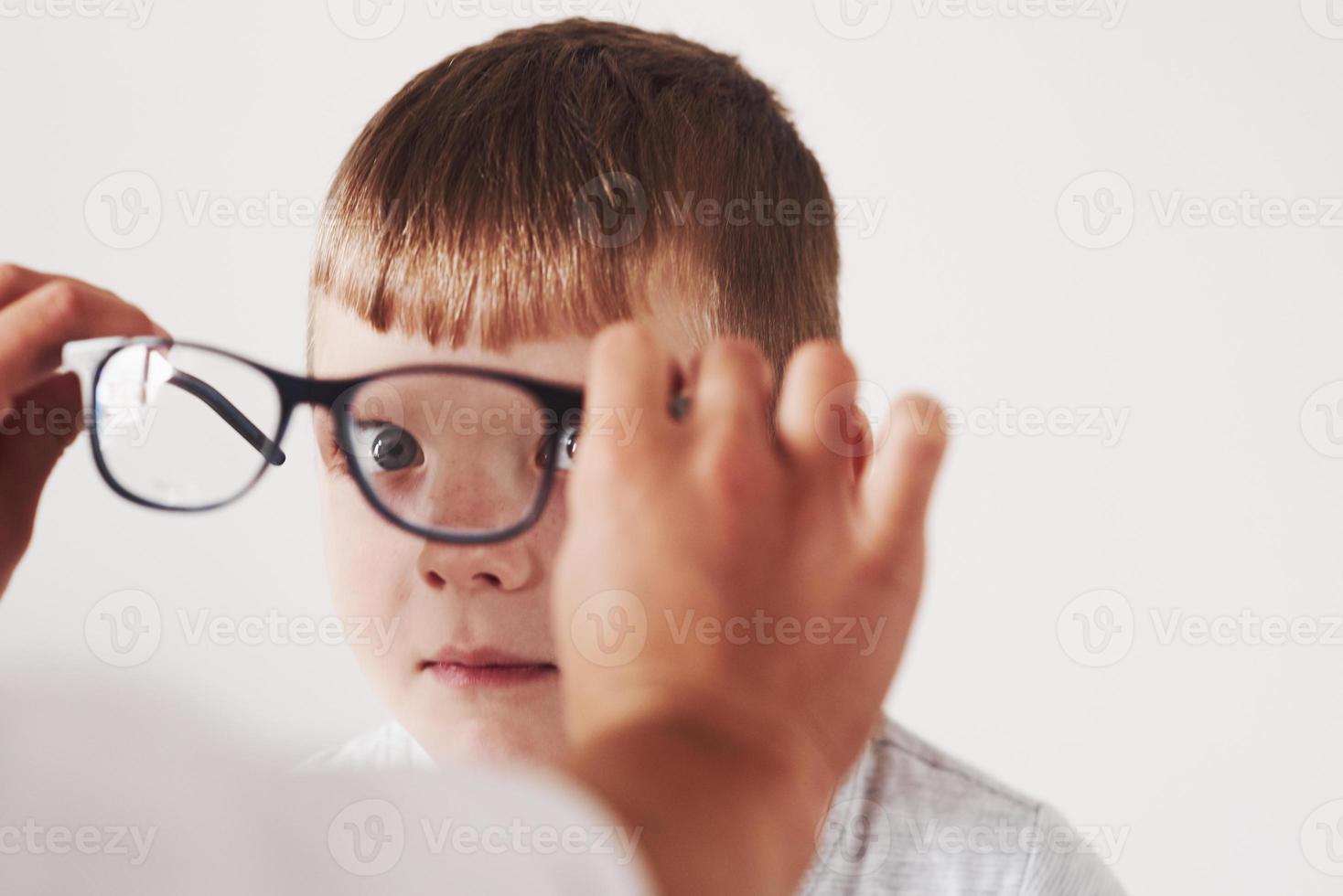 s'amuser. médecin donnant à l'enfant de nouvelles lunettes noires pour sa vision photo