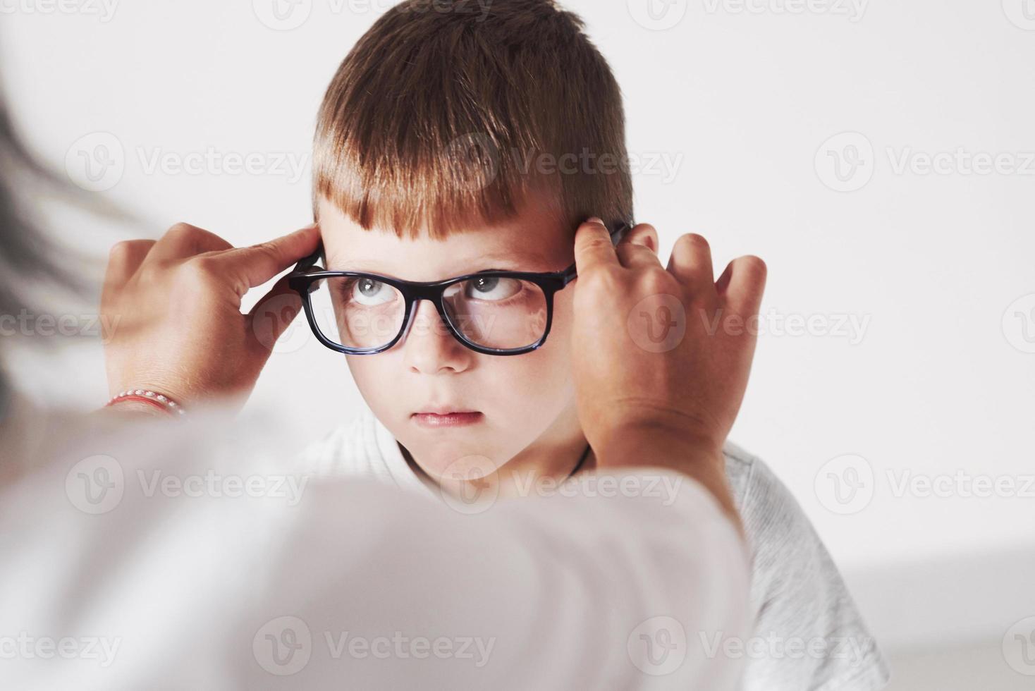 enfant drôle. médecin donnant à l'enfant de nouvelles lunettes noires pour sa vision photo