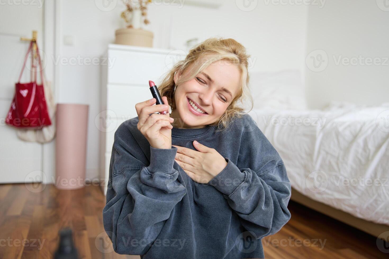 portrait de Jeune contenu créateur, femme avec social médias compte, enregistrement à propos maquillage sur numérique caméra, en portant préféré rouge à lèvres, recommander produit à public en ligne photo