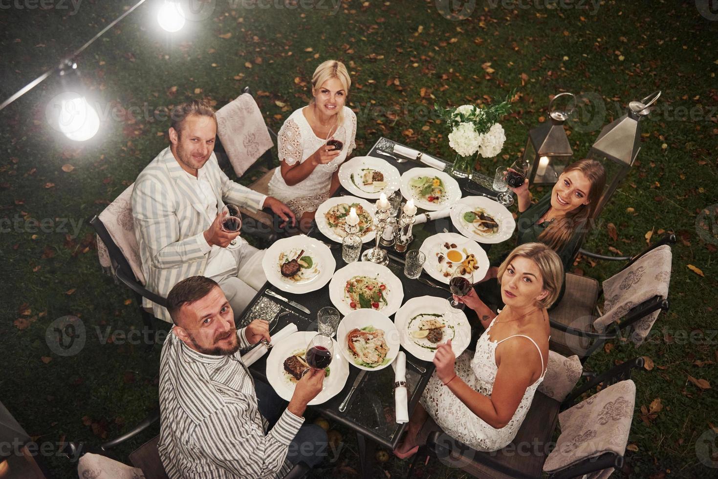 Regardez tous dans la caméra s'il vous plaît. vue de dessus. un groupe d'amis en tenue élégante a un dîner de luxe photo