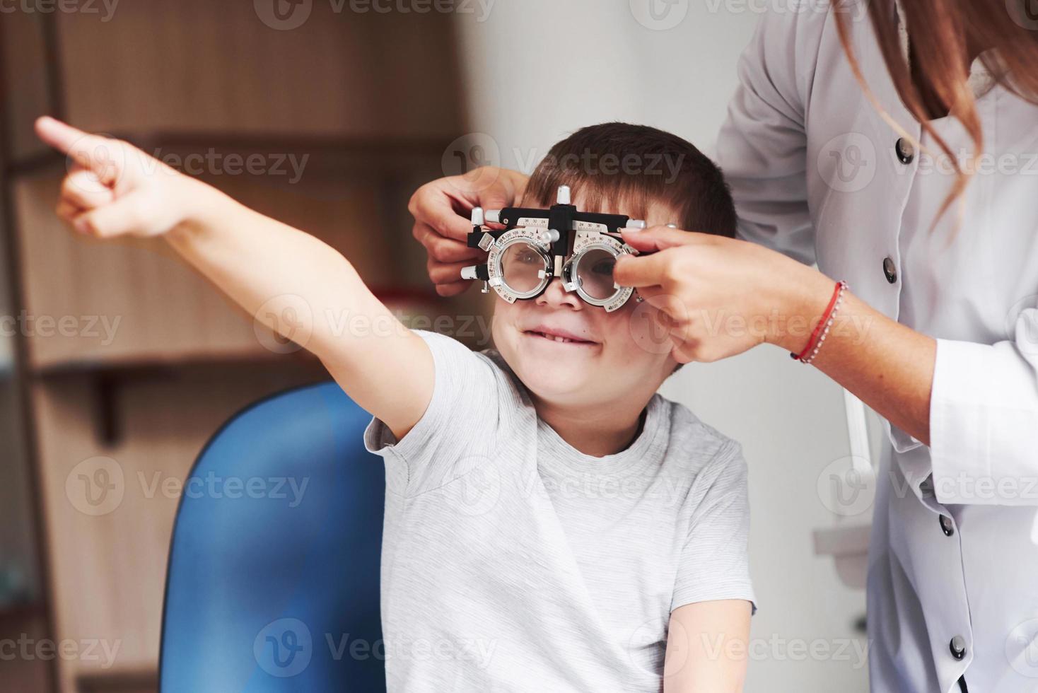 je vois ça plutôt bien. enfant assis dans le cabinet du médecin et ont testé son acuité visuelle photo