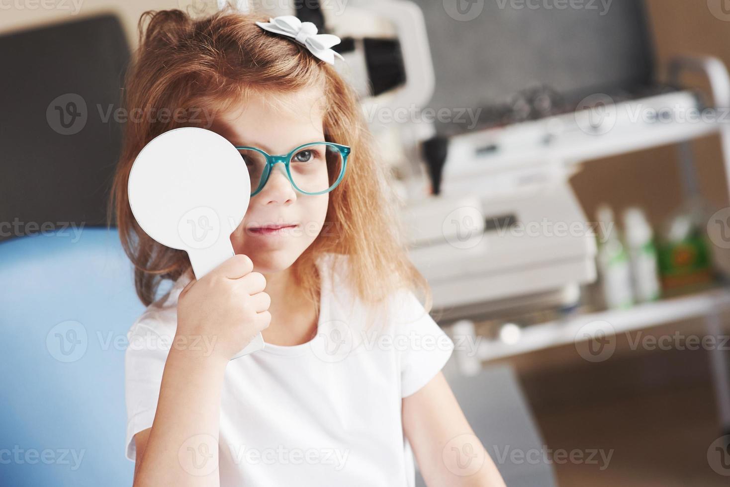 pas de triche, nous voulons que ce test se passe correctement. petite fille vérifiant sa vision avec de nouvelles lunettes vertes photo