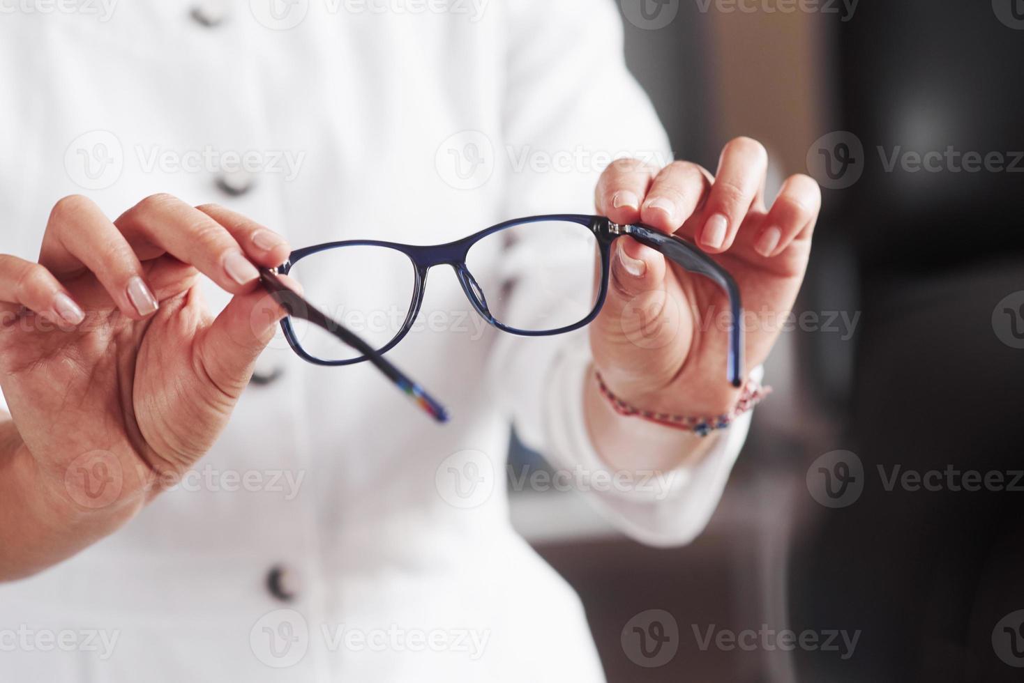 les mains de la femme tiennent les lunettes bleues dans le cabinet du médecin photo