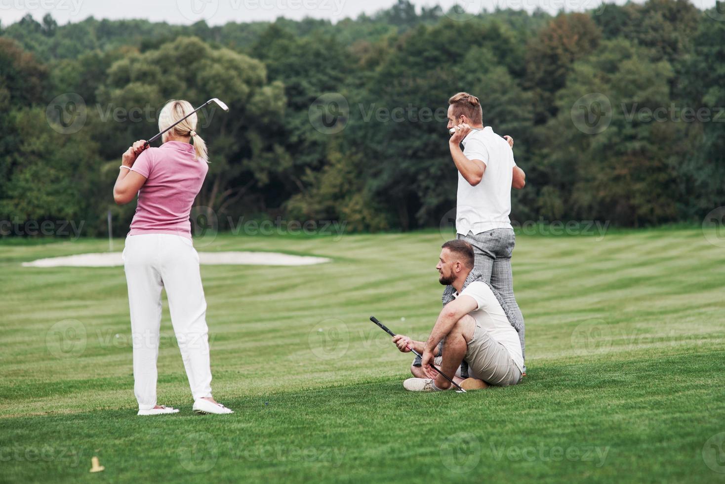 regarder le ballon. trois amis passent du bon temps sur le terrain à jouer au golf et à regarder le tir photo