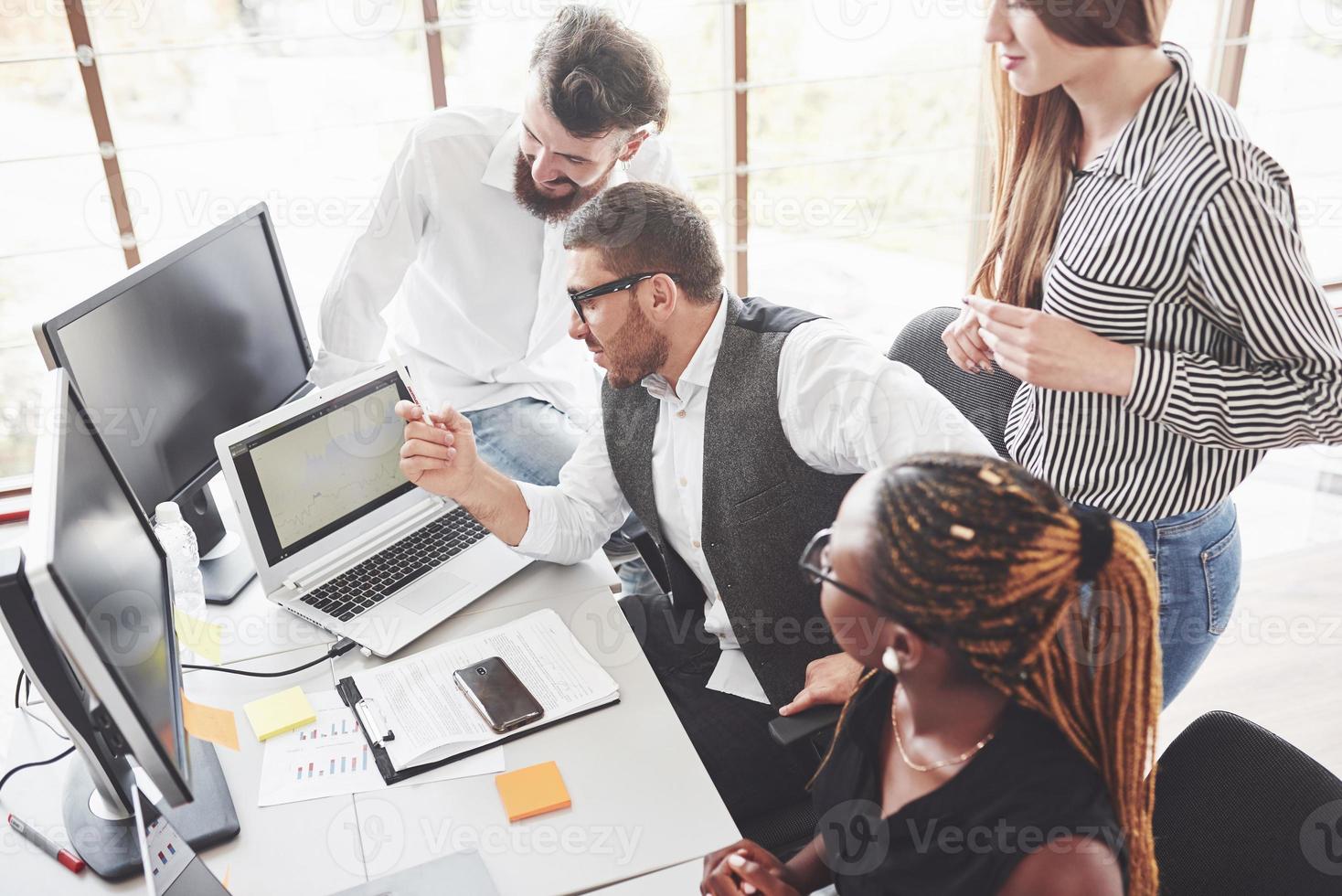 comparer les graphiques sur ordinateur portable. les travailleurs de l'équipe se réunissent et discutent de la planification de leur entreprise photo