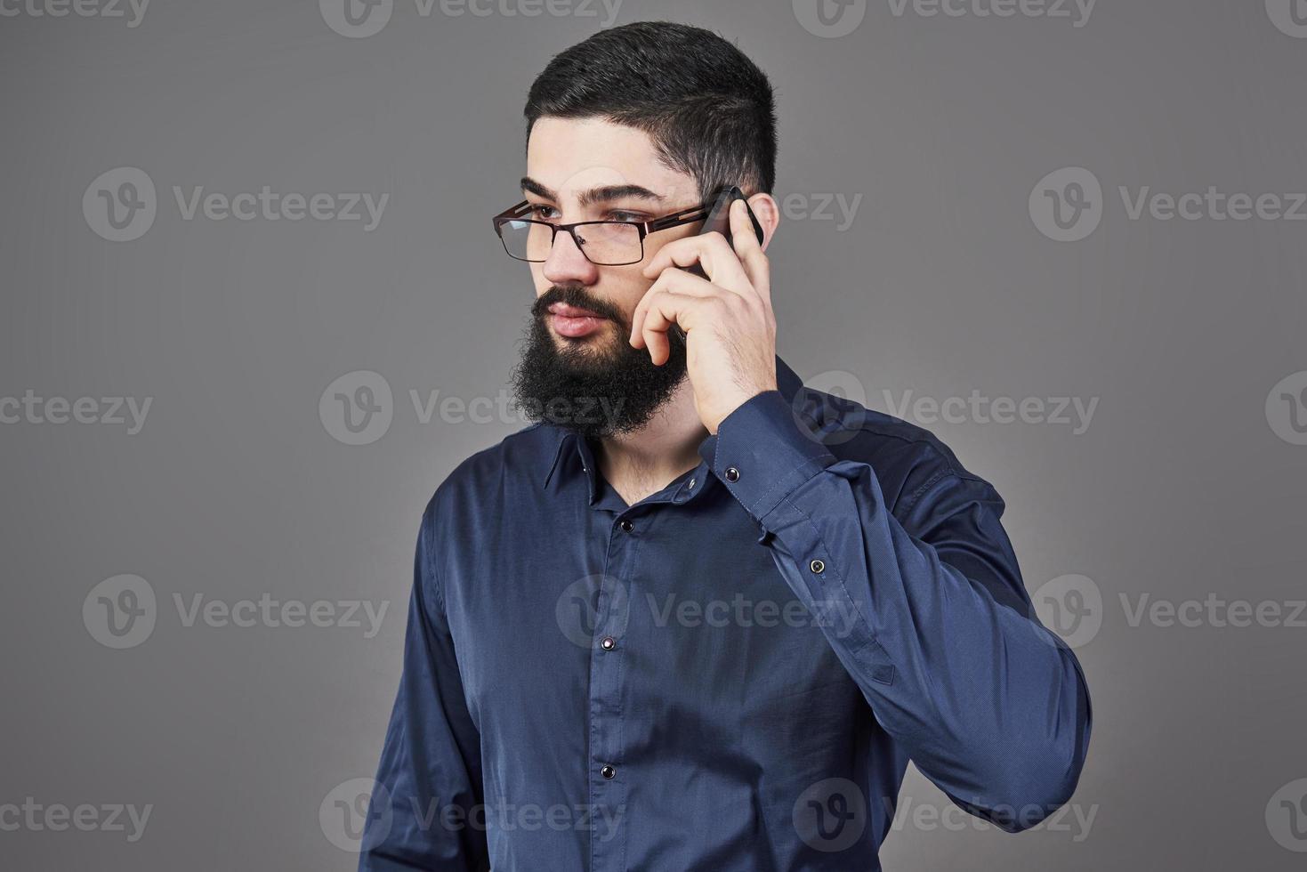 homme heureux à lunettes parle par téléphone sur fond gris photo