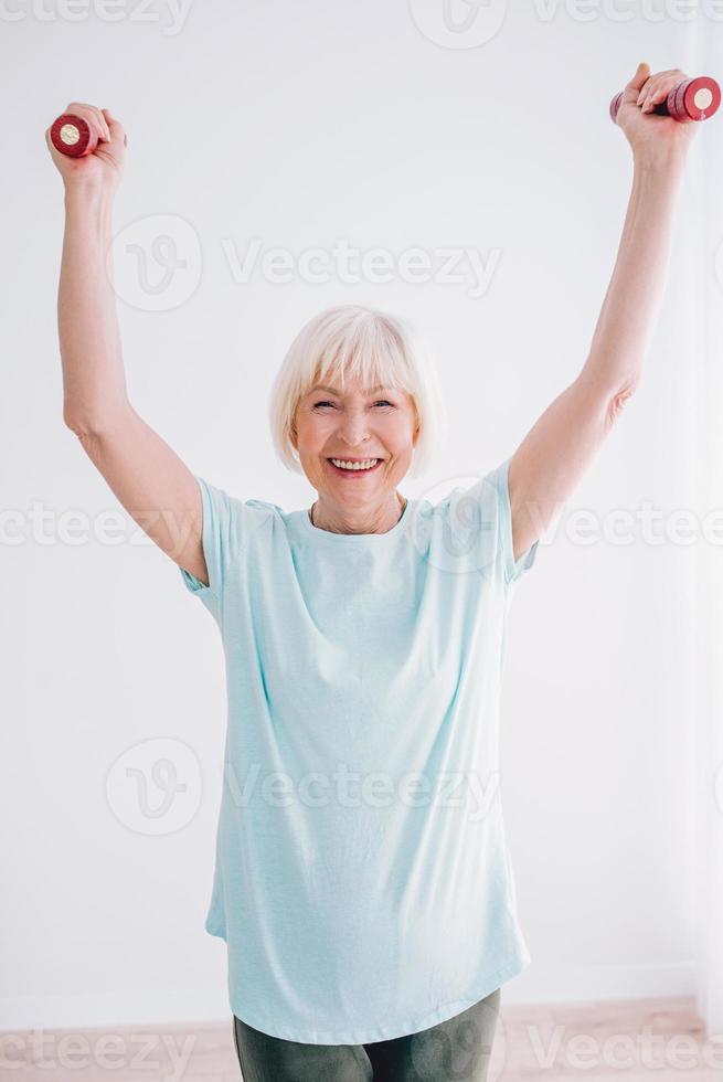 femme joyeuse senior faisant du sport avec des haltères. anti-âge, sport, concept de mode de vie sain photo