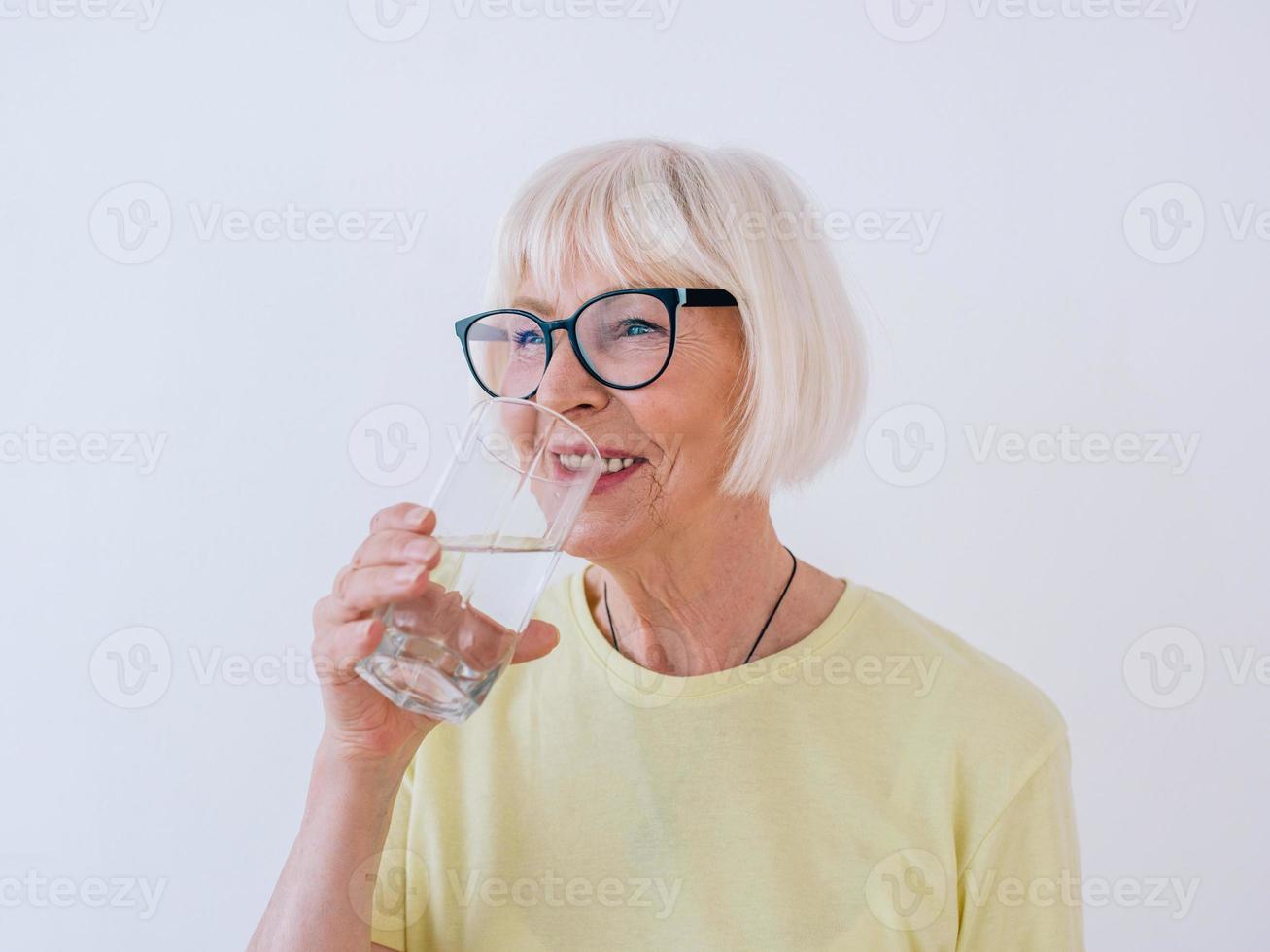 femme âgée tenant un verre d'eau et d'eau potable. mode de vie sain, sport, concept anti-âge photo