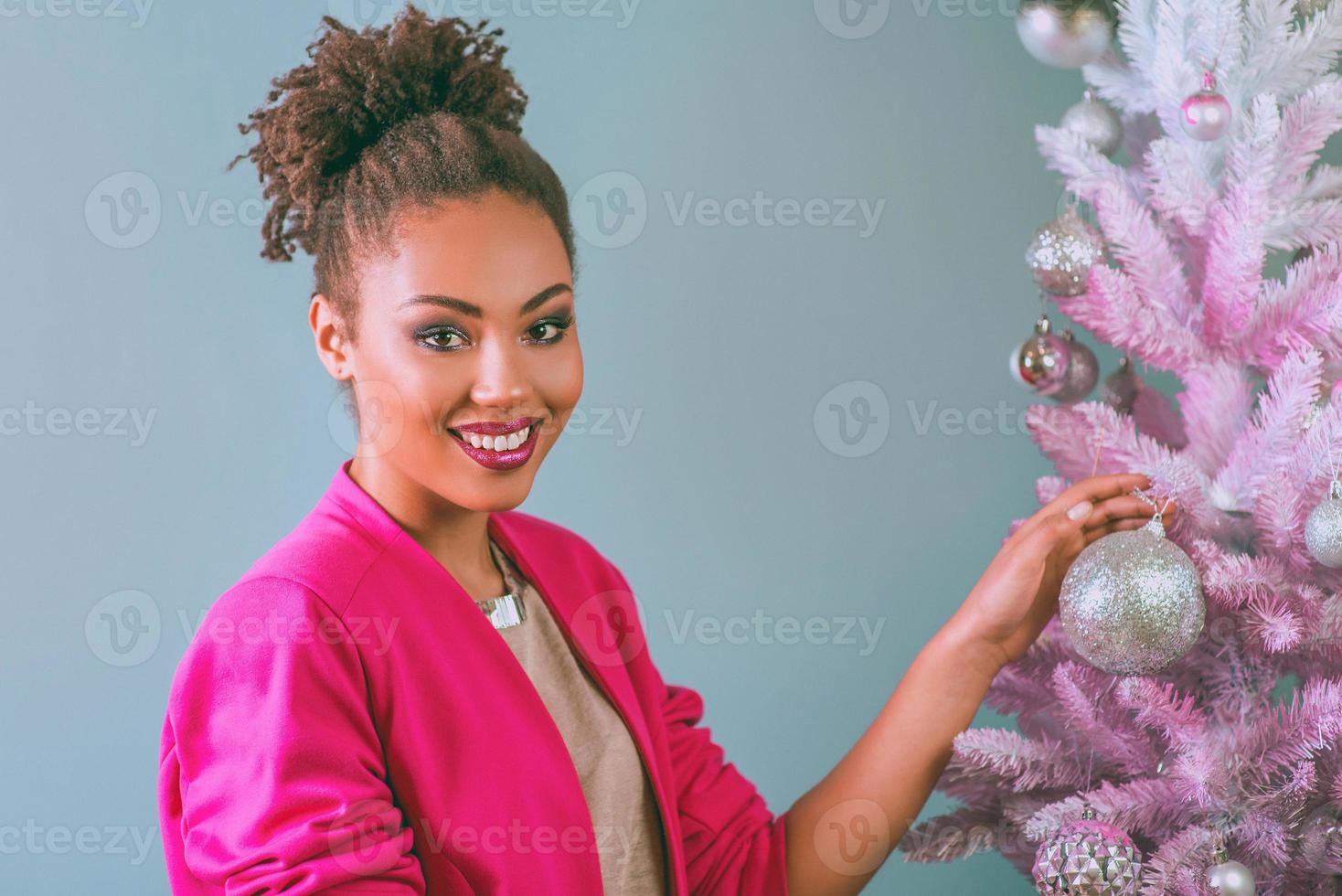 femme afro-américaine heureuse et gaie avec boîte présente sur le fond de l'arbre de noël. noël, nouvel an, bonheur, concept de vacances photo