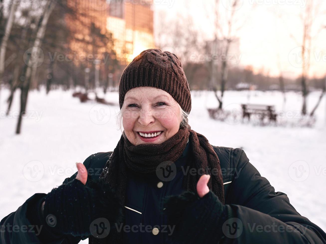 femme âgée au chapeau et veste sportive faisant des exercices sportifs dans le parc d'hiver de neige. hiver, âge, sport, activité, concept de saison photo
