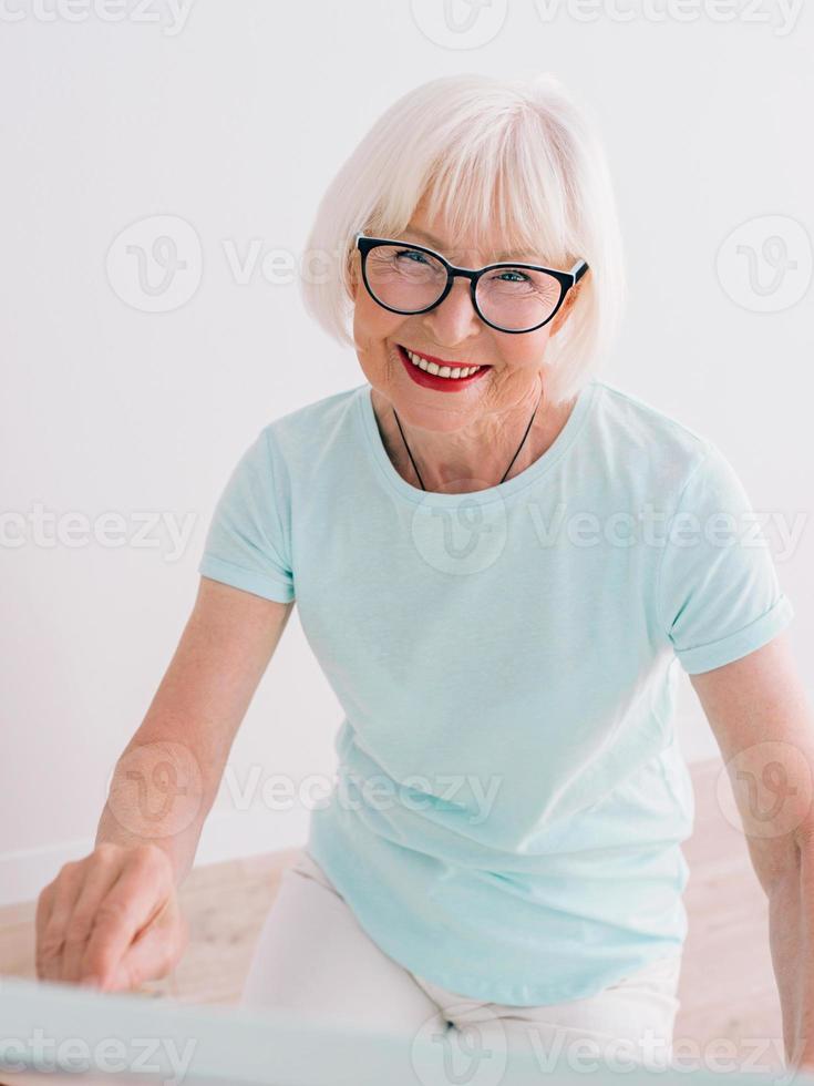 artiste senior femme joyeuse dans des verres avec des cheveux gris dessin avec des fleurs au crayon dans un vase. créativité, art, passe-temps, concept d'occupation photo