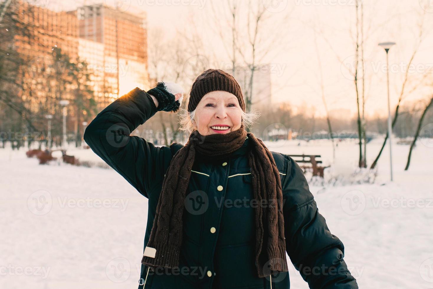 femme âgée au chapeau et veste sportive faisant des exercices sportifs dans le parc d'hiver de neige. hiver, âge, sport, activité, concept de saison photo