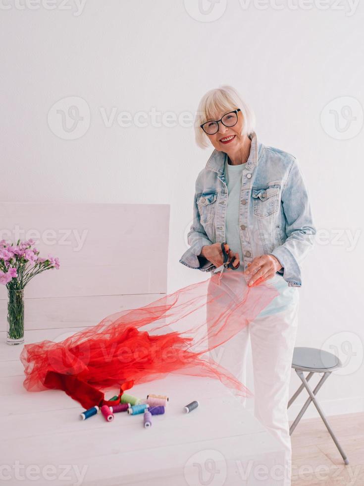 retraité senior gai créateur de vêtements femme élégante en veste en jean au travail. fait main, mode, passe-temps, design, concept d'âge photo