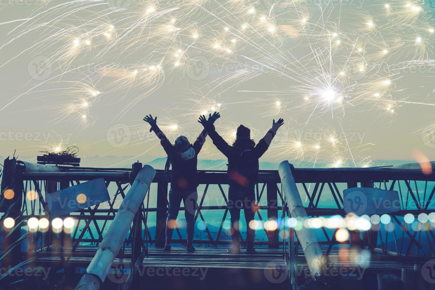 amant femmes et hommes asiatiques. tenez-vous debout et levez les mains pour regarder les feux d'artifice. heureux le jour de la célébration du nouvel an sur la montagne en thaïlande. photo