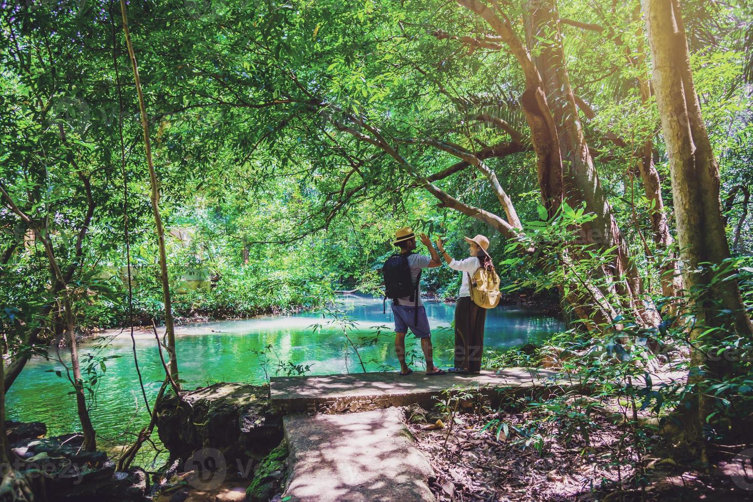 voyageurs, couples avec sacs à dos de voyage naturels pendant les vacances. les couples voyageant, se relaxant dans la jungle verte et profitant du magnifique étang émeraude. tourisme, randonnée, étude de la nature. photo