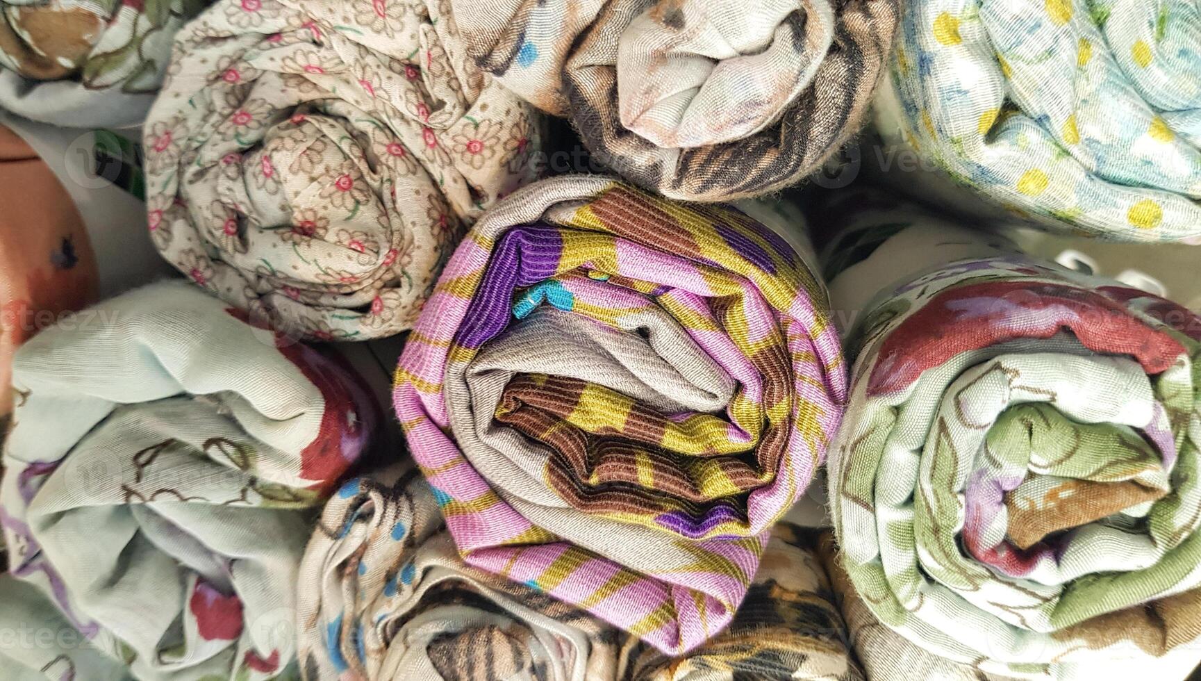 piles de hijabs, foulards de divers couleurs dans Rouleaux, Photos de piles de coloré hijabs roulé en haut sur afficher cas. photo Contexte