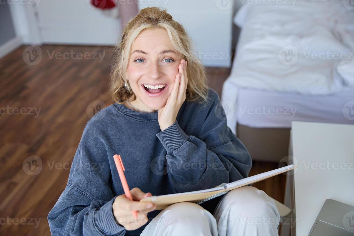 portrait de content, Jeune blond femme, séance dans chambre avec carnet et stylo, en riant et souriant, l'écriture dans journal, Faire devoirs et souriant photo