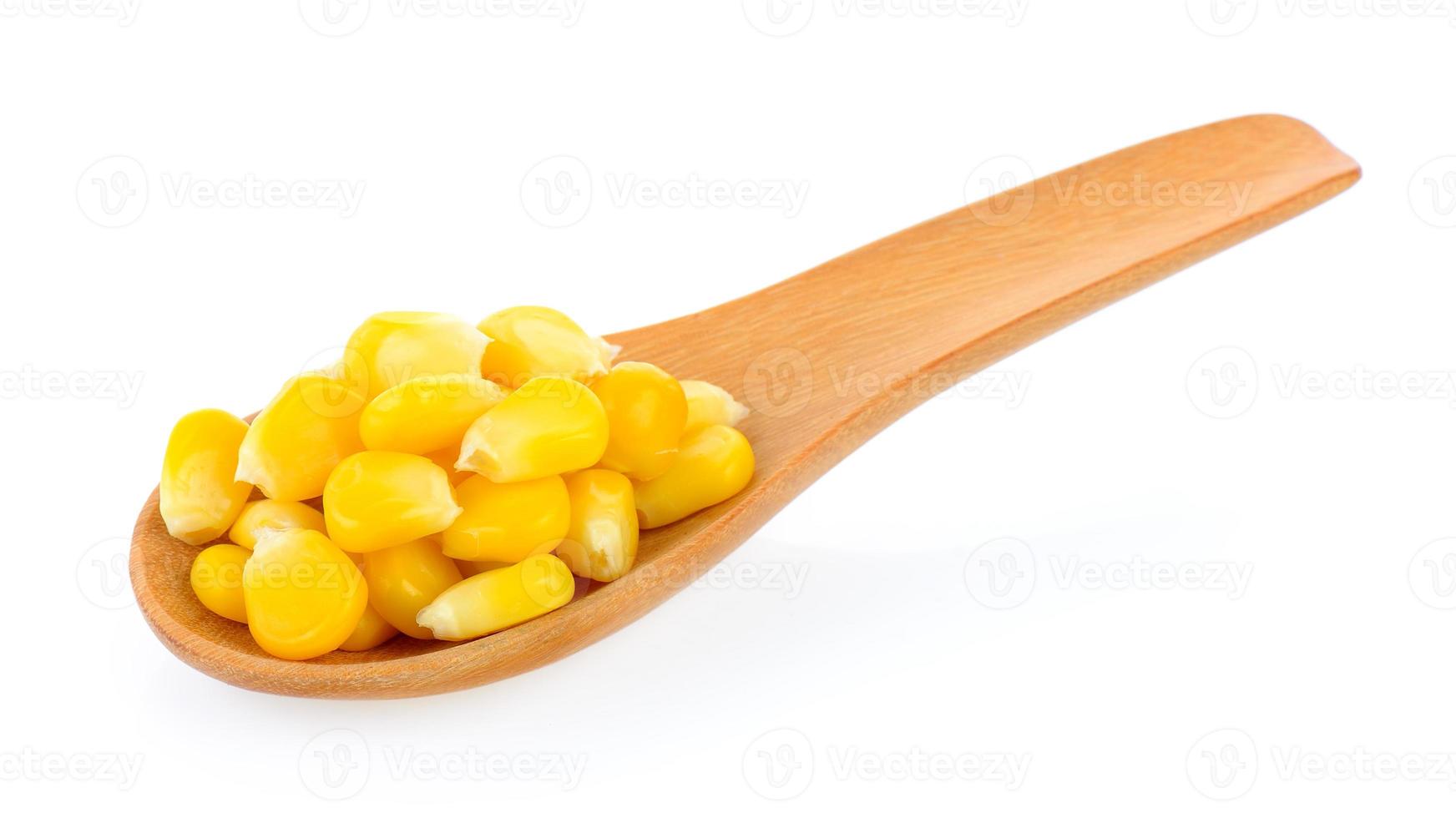 Graines de maïs en cuillère de bois sur fond blanc photo