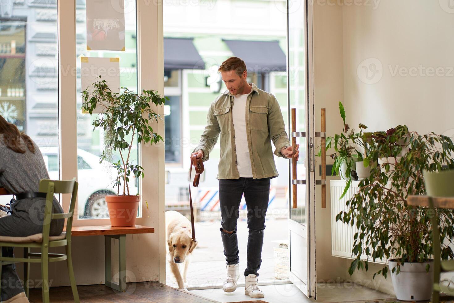 portrait de Beau Jeune homme des promenades dans le café avec le sien chien sur une laisse, entre dans acceptant les animaux café boutique, ouvre le porte photo