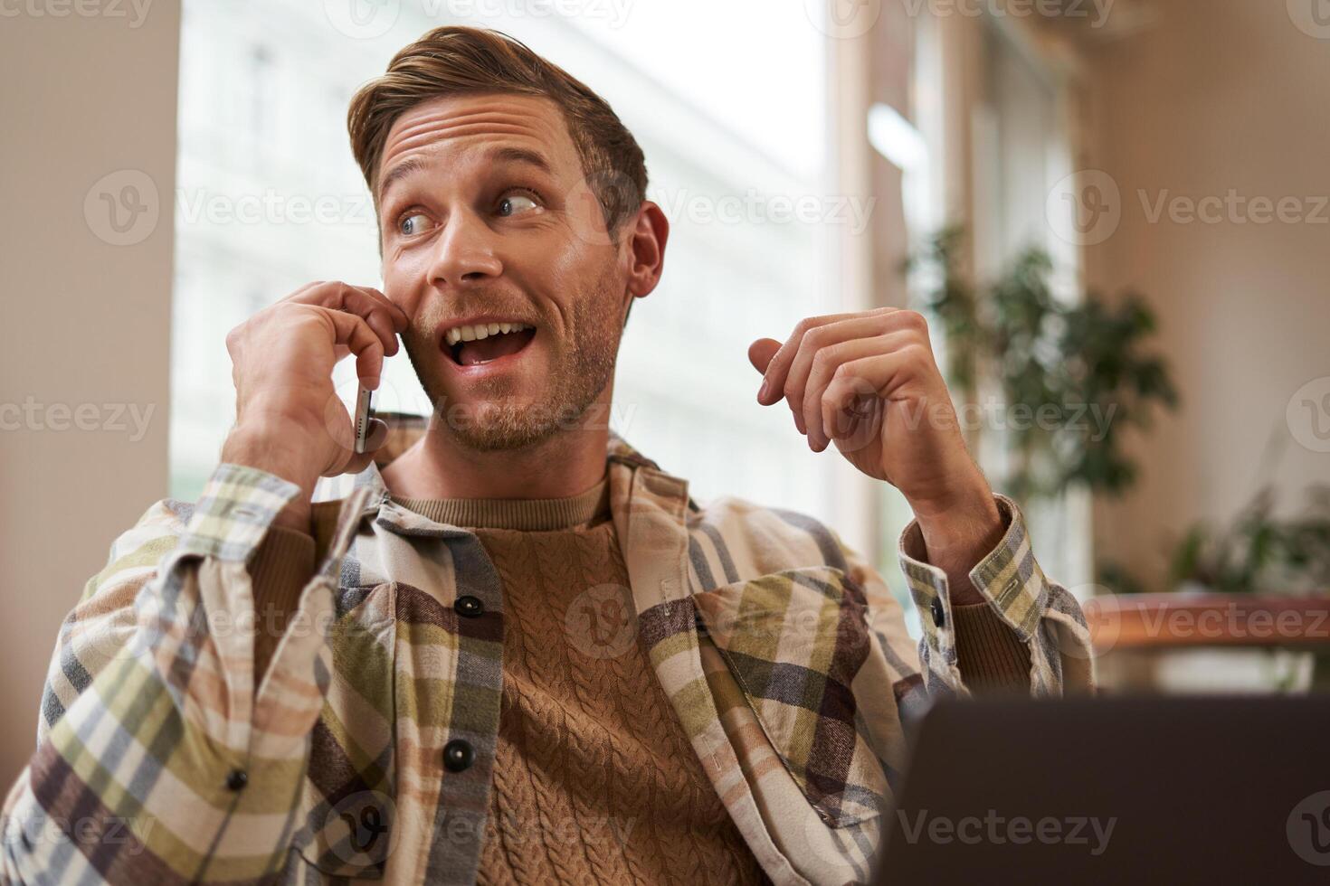 free-lance, numérique nomade et espace de travail concept. portrait de Beau Jeune homme avec mobile téléphone, séance dans café avec ordinateur portable, travail sur projet, en train d'étudier à distance, à la recherche retour à l'extérieur fenêtre photo