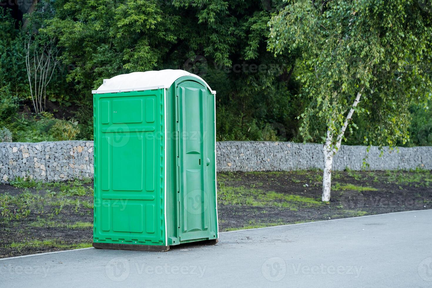 un Extérieur bio toilette des stands sur le trottoir dans une ville parc, une vert Plastique toilettes, une cabine pour toilettes. photo