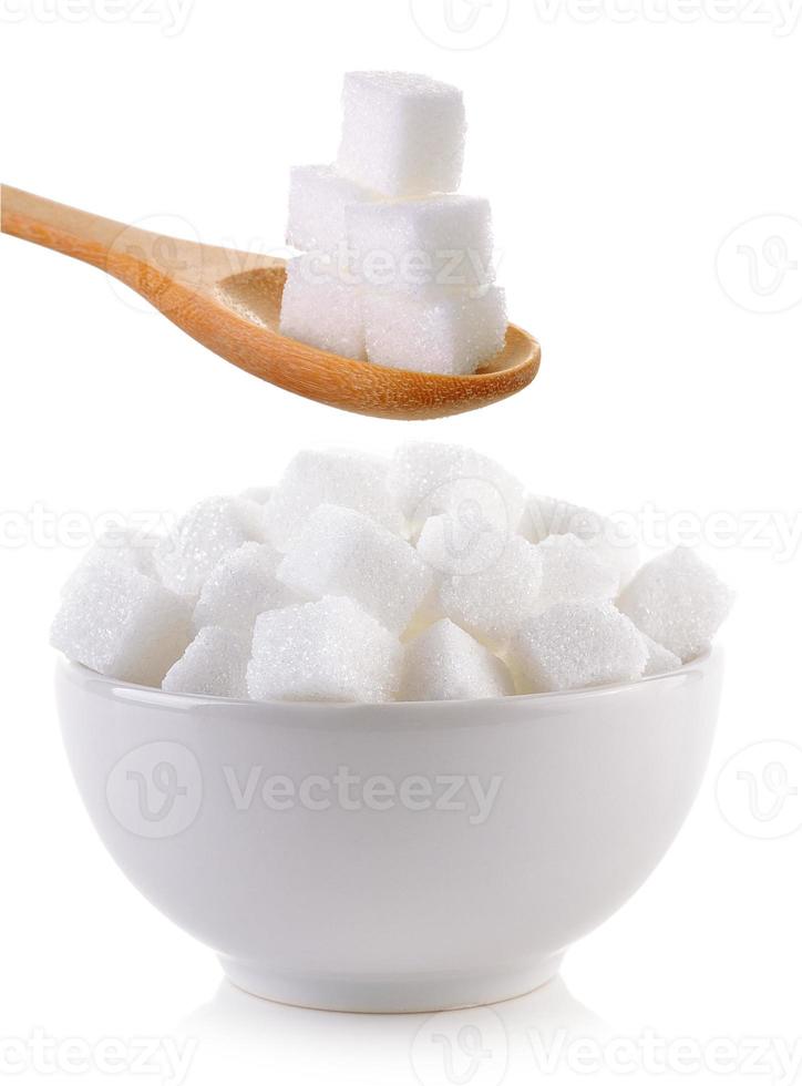 cube de sucre dans le bol et cuillère en bois sur fond blanc photo