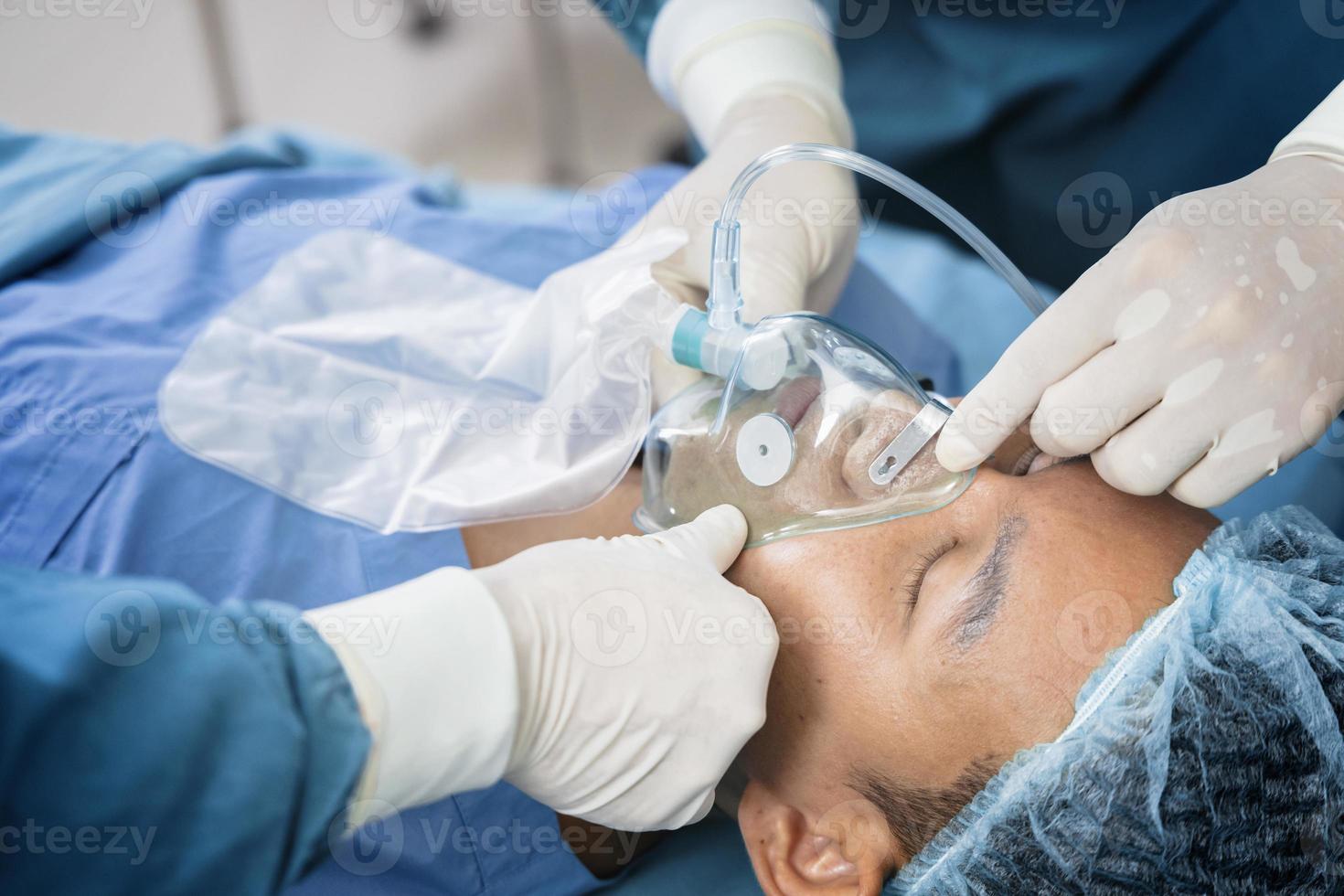 le chirurgien assistant a mis le patient sur un masque de ventilation-oxygène en vue de la chirurgie. photo