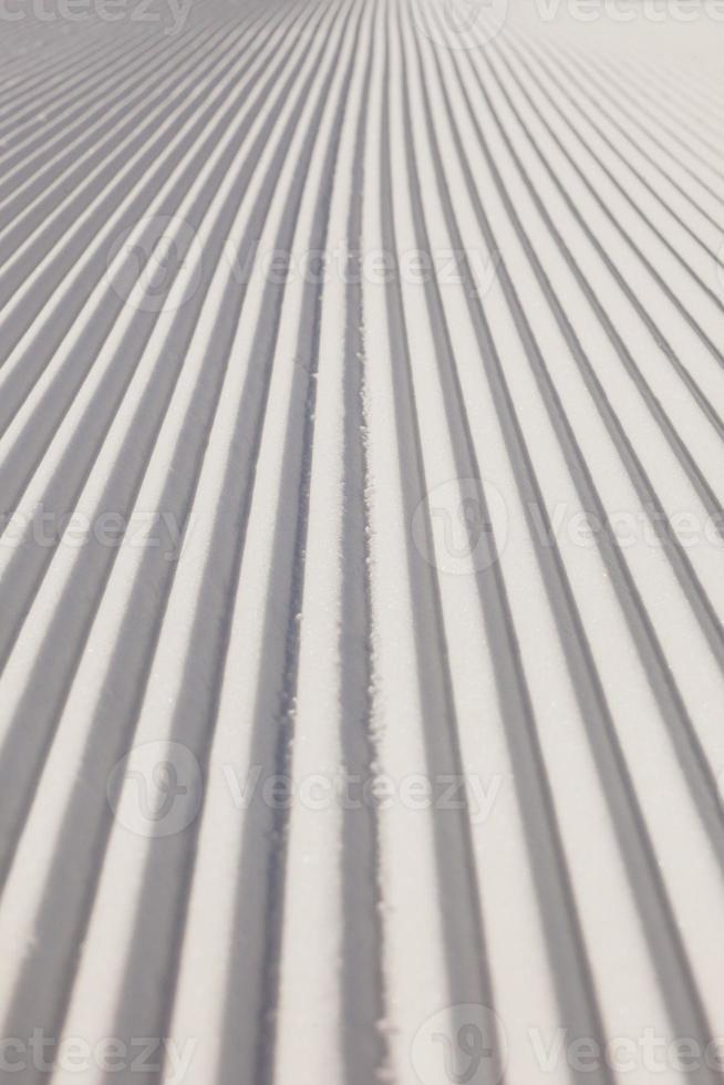 texture de la nouvelle neige damée sur une piste de ski vide photo