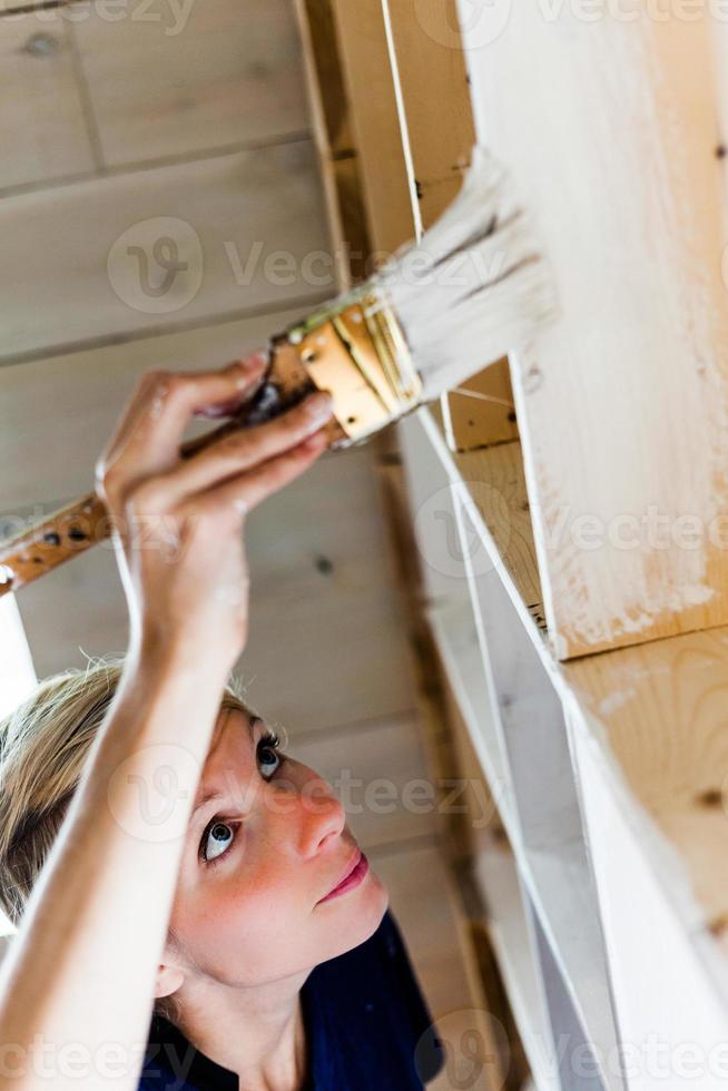 femme appliquant la première couche de peinture sur une bibliothèque en bois photo