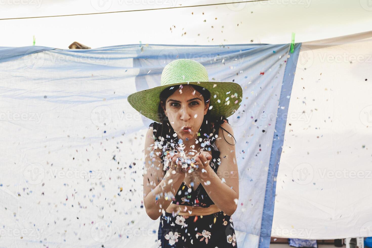 jolie femme avec coloré paille chapeau soufflant confettis photo