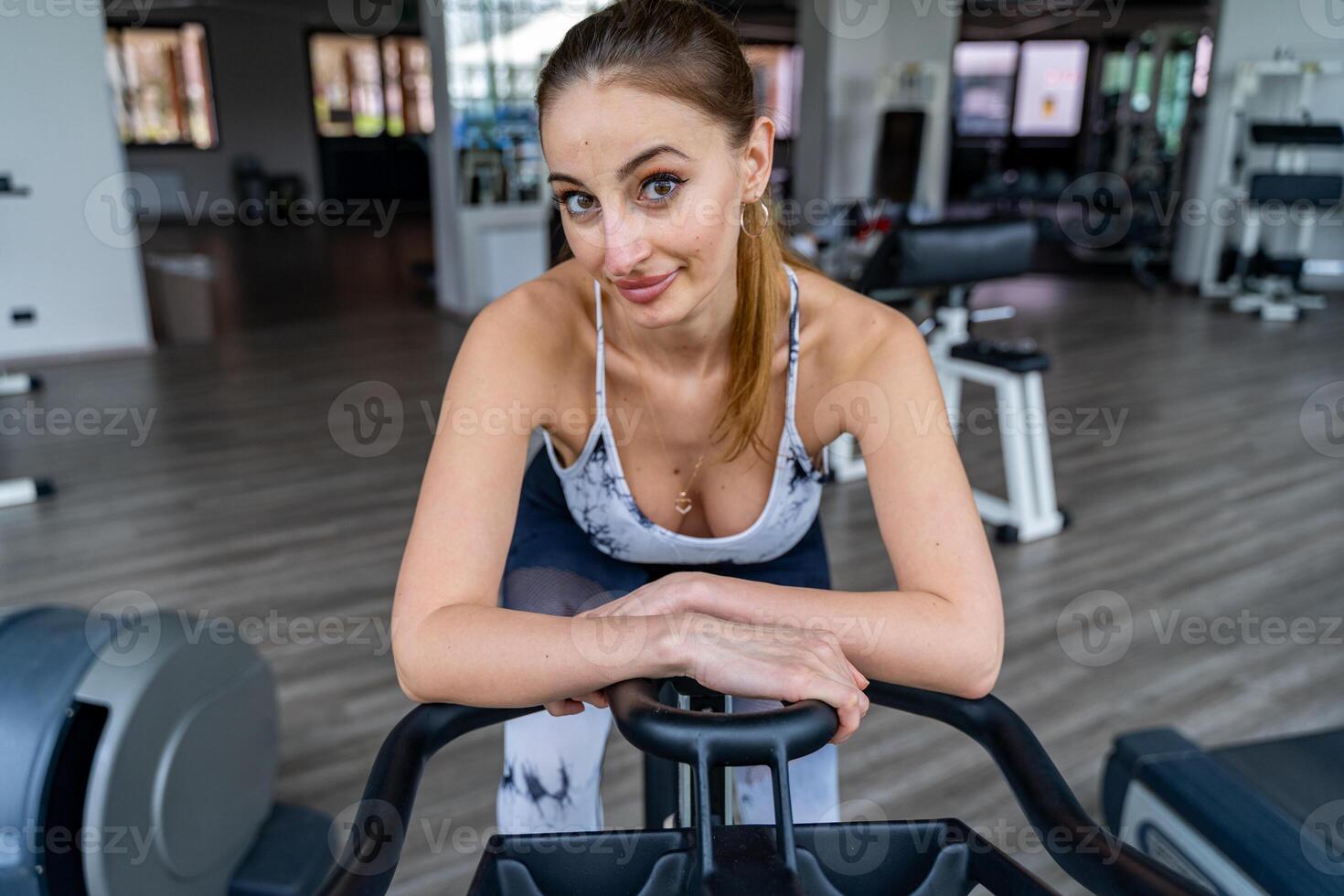 Jeune mignonne femme dans serré des sports costume formation sur exercice bicyclette dans Gym photo