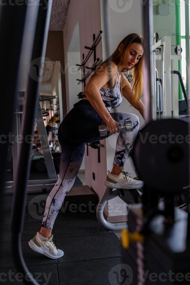 Jeune charmant blond femme dans tenue de sport levage haltères dans une Gym photo