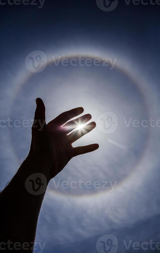 silhouette de la main avec un halo de soleil circulaire photo